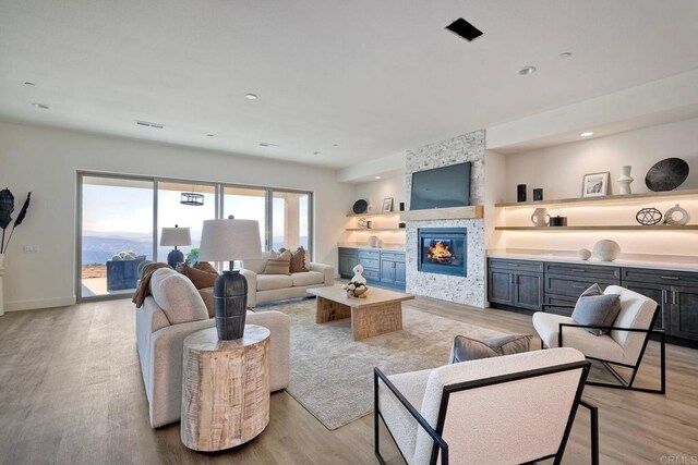 living room with light wood-type flooring and a stone fireplace