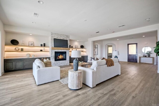 living room with light hardwood / wood-style flooring and a stone fireplace