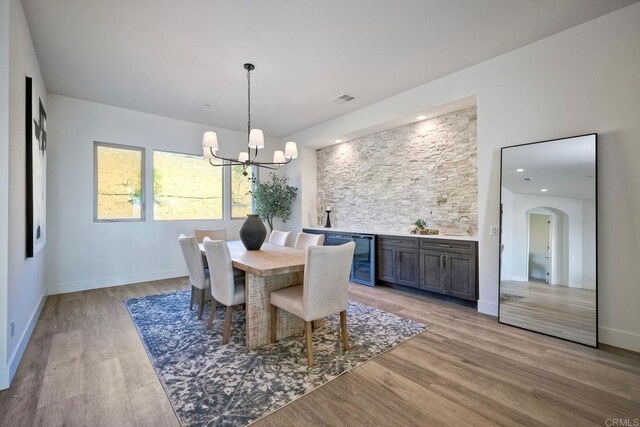 dining area featuring an inviting chandelier, wine cooler, and light hardwood / wood-style flooring