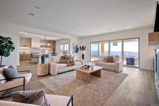 living room featuring a mountain view, light hardwood / wood-style flooring, and a chandelier