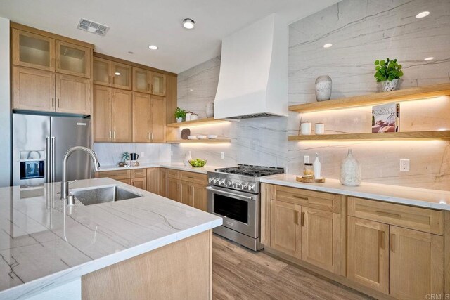 kitchen with premium range hood, light hardwood / wood-style floors, decorative backsplash, sink, and stainless steel appliances