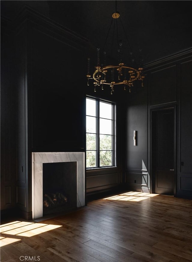 unfurnished living room with a fireplace, wood-type flooring, and a notable chandelier