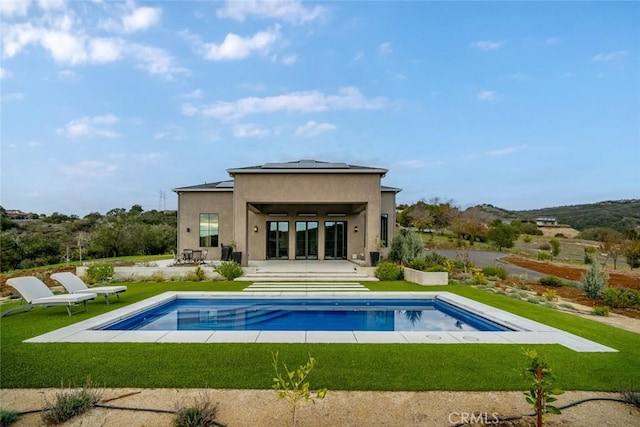 back of property featuring solar panels, a lawn, and a patio