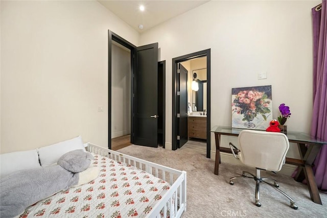 bedroom with ensuite bathroom and light carpet