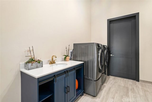 laundry area featuring light hardwood / wood-style flooring, sink, separate washer and dryer, and cabinets