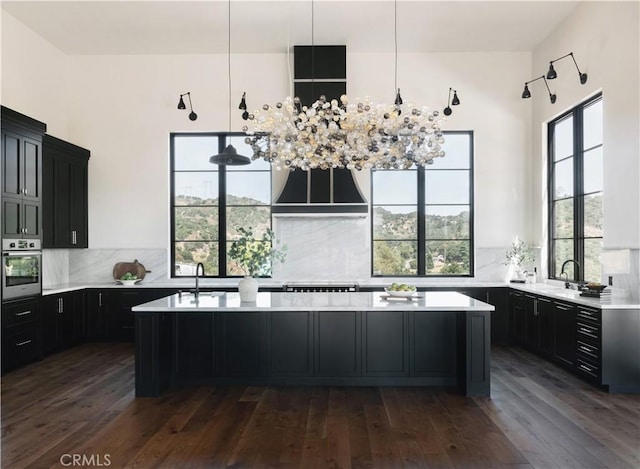 kitchen featuring decorative backsplash, sink, dark wood-type flooring, oven, and a center island