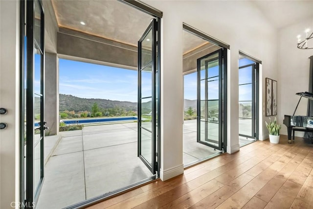 entryway featuring light wood-type flooring, plenty of natural light, a mountain view, and a chandelier