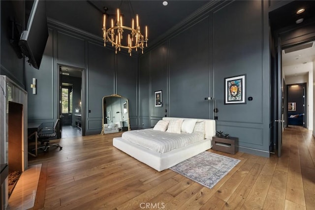 bedroom featuring light wood-type flooring, a towering ceiling, and a notable chandelier