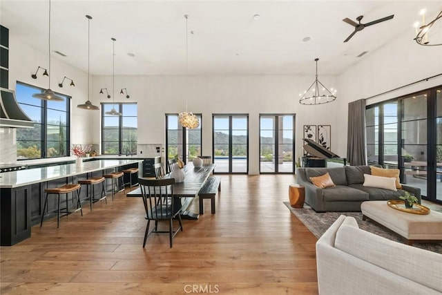 dining room featuring ceiling fan, light hardwood / wood-style floors, and a towering ceiling