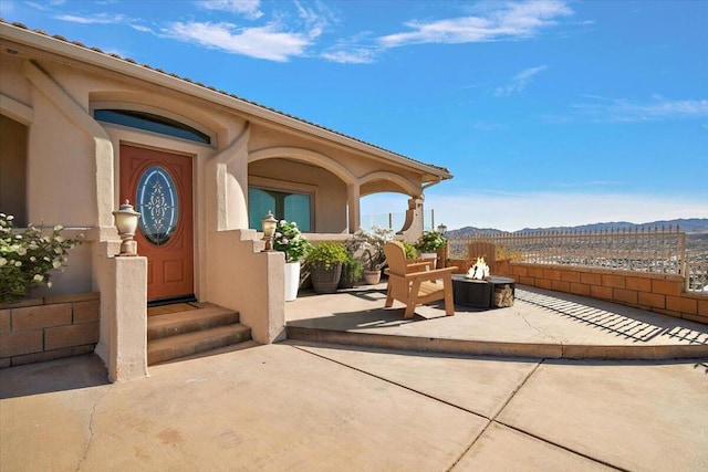 view of exterior entry with a mountain view and a patio