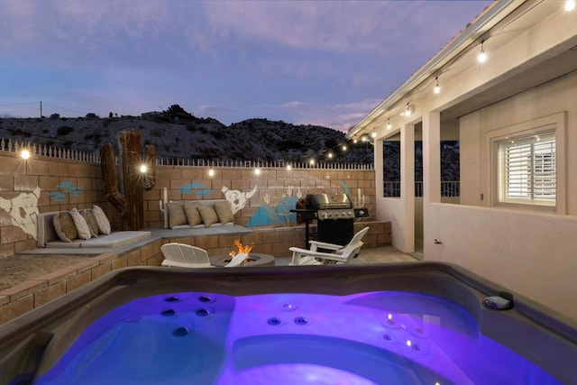 pool at dusk with a hot tub and area for grilling