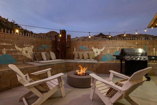 patio terrace at dusk with an outdoor fire pit and area for grilling