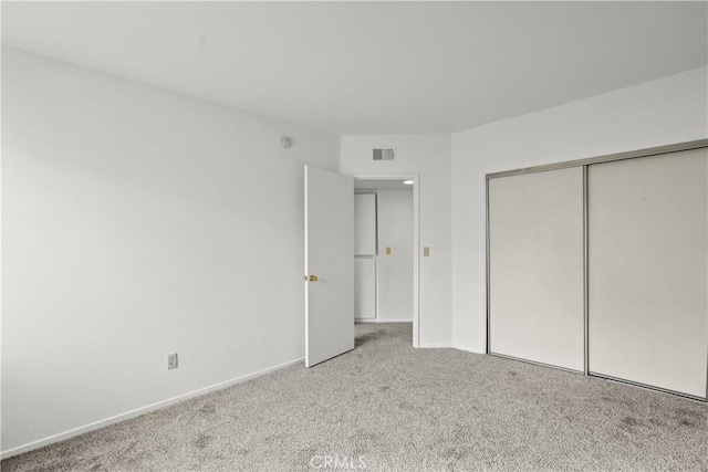 unfurnished bedroom featuring a closet and light carpet