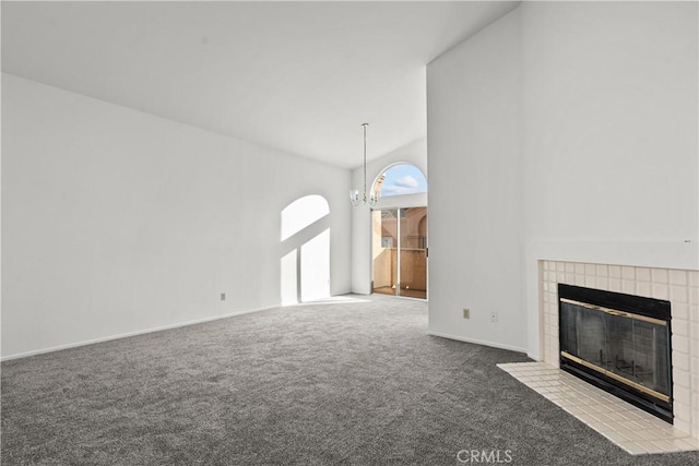 unfurnished living room with a chandelier, carpet flooring, a tiled fireplace, and high vaulted ceiling