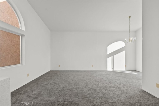 carpeted spare room featuring a notable chandelier