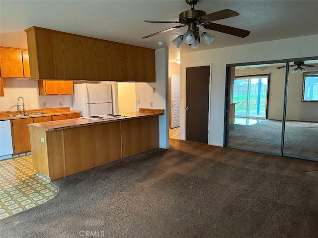 kitchen with sink, white appliances, light carpet, and kitchen peninsula