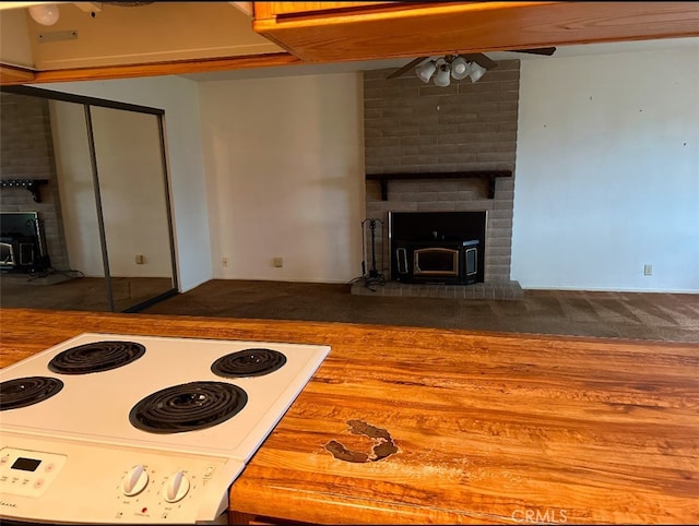 kitchen featuring ceiling fan, a wood stove, white range with electric stovetop, and wood counters