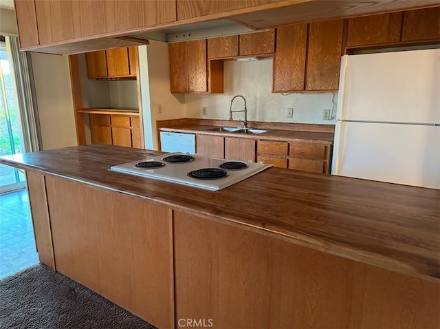 kitchen with dark colored carpet, sink, butcher block counters, and white appliances