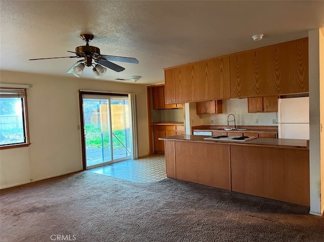 kitchen with white appliances, a textured ceiling, kitchen peninsula, ceiling fan, and light colored carpet