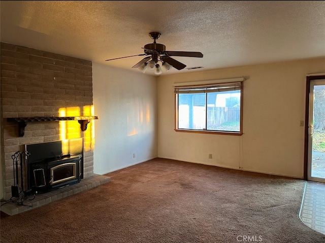 unfurnished living room featuring a textured ceiling, ceiling fan, carpet, and a wood stove