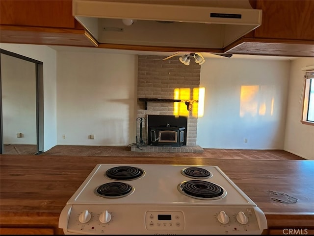 kitchen with ceiling fan, range with electric stovetop, and a wood stove