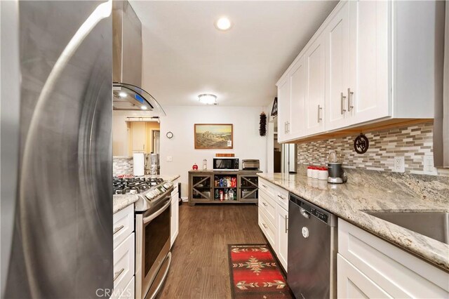 kitchen with stainless steel appliances, tasteful backsplash, dark wood-type flooring, light stone countertops, and white cabinets