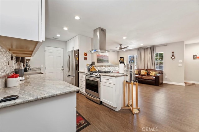 kitchen with backsplash, island exhaust hood, stainless steel appliances, and white cabinetry