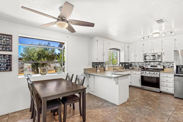 kitchen with white cabinets, appliances with stainless steel finishes, sink, kitchen peninsula, and ceiling fan