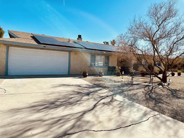 ranch-style house featuring a garage and solar panels