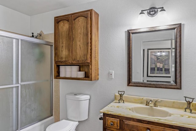 full bathroom with bath / shower combo with glass door, toilet, and vanity