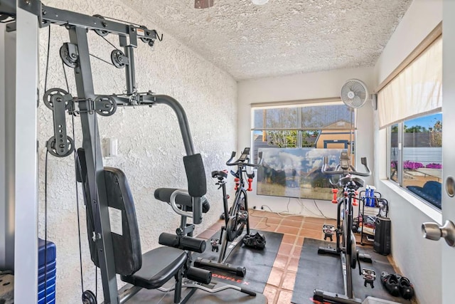 workout room with tile patterned flooring, a textured ceiling, and a healthy amount of sunlight