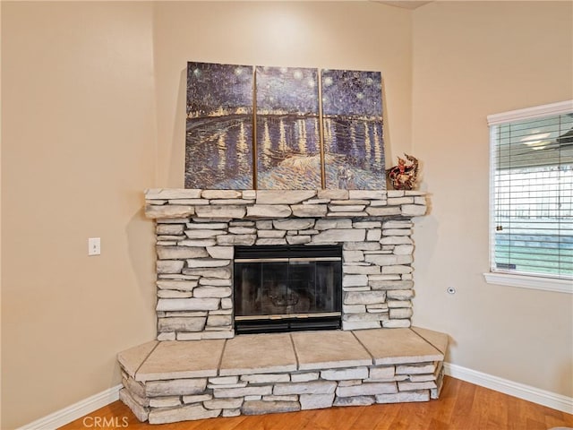 room details with hardwood / wood-style flooring and a stone fireplace