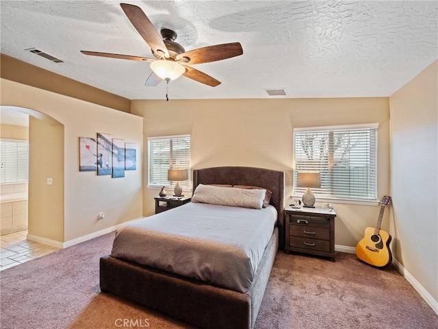 bedroom featuring ceiling fan, light colored carpet, and a textured ceiling