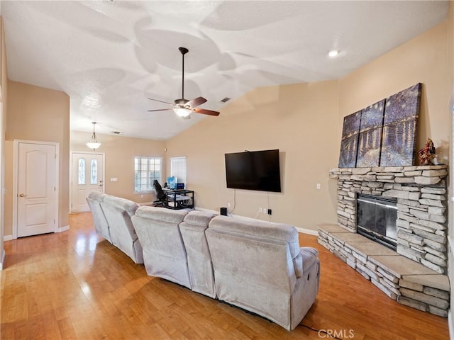 living room featuring light wood-type flooring, ceiling fan, lofted ceiling, and a fireplace