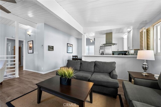 living room featuring hardwood / wood-style floors, sink, wooden ceiling, and beamed ceiling