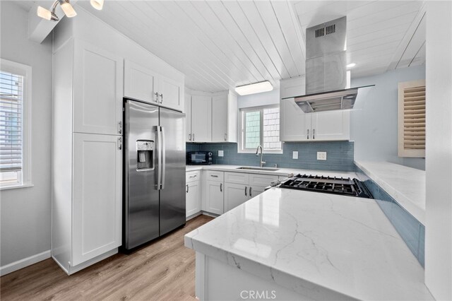 kitchen featuring sink, stainless steel appliances, light stone counters, island range hood, and white cabinets
