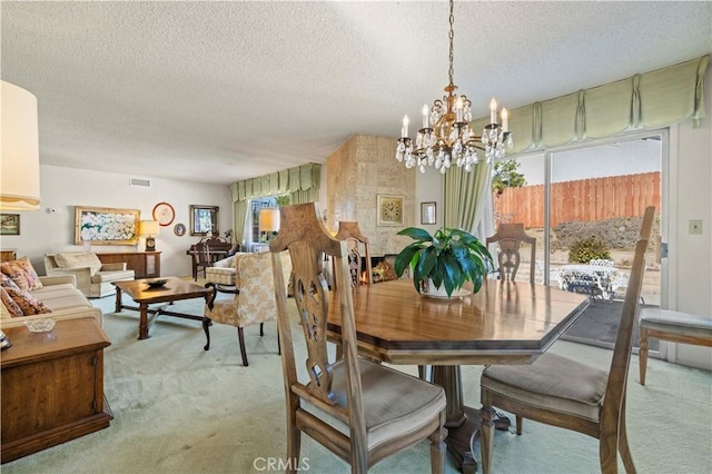 dining space featuring light colored carpet, a notable chandelier, and a textured ceiling