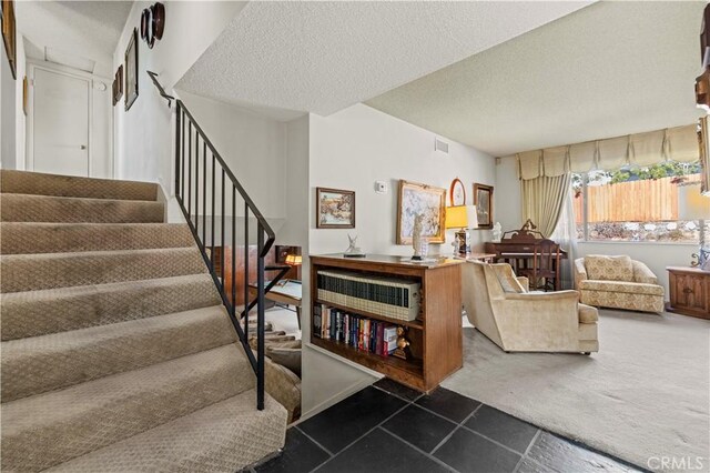 stairway featuring a textured ceiling and carpet flooring