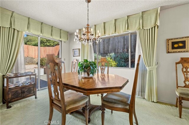 dining space with a textured ceiling, light carpet, and a notable chandelier