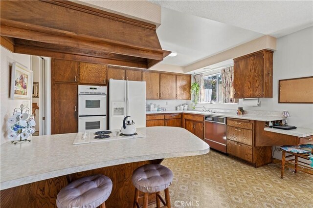 kitchen featuring a breakfast bar, kitchen peninsula, and white appliances