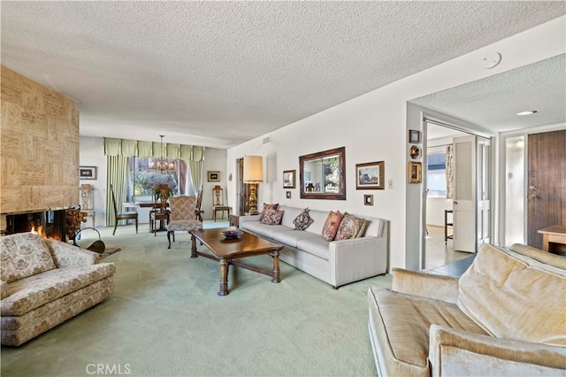 carpeted living room featuring a textured ceiling, a chandelier, and a large fireplace