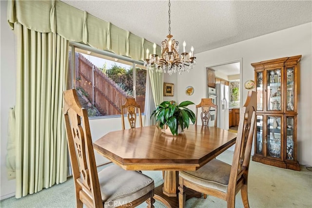 carpeted dining space featuring a textured ceiling, a healthy amount of sunlight, and an inviting chandelier