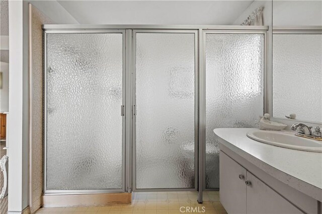 bathroom featuring an enclosed shower, vanity, and lofted ceiling