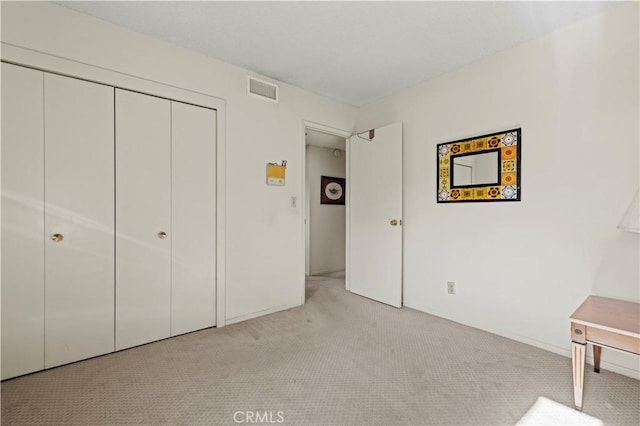 unfurnished bedroom with light colored carpet and a closet