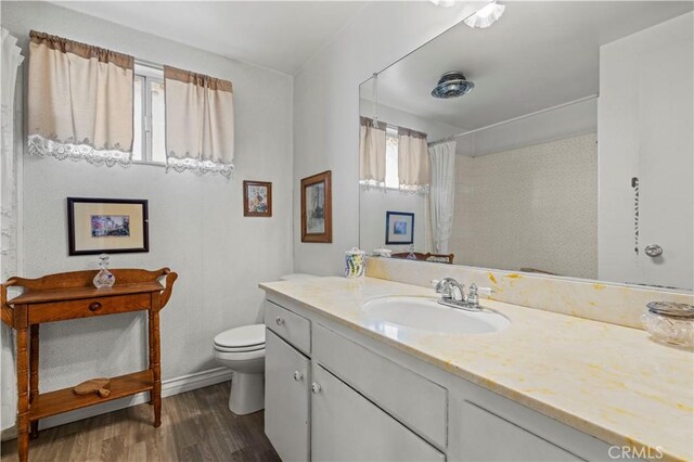 bathroom featuring toilet, a shower with shower curtain, hardwood / wood-style floors, and vanity