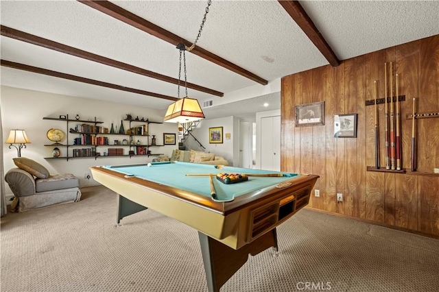 game room with carpet flooring, a textured ceiling, beam ceiling, and wood walls