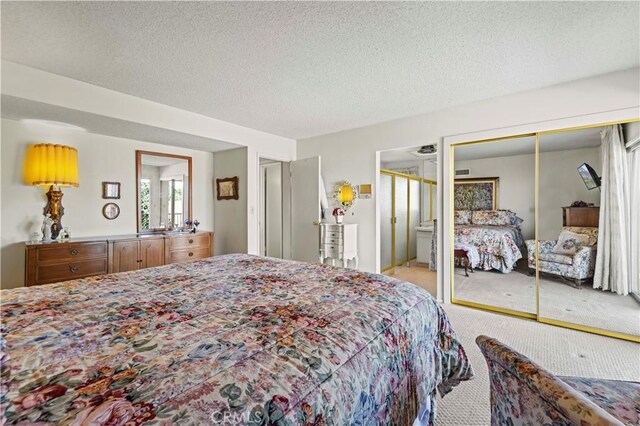 carpeted bedroom with ensuite bath, a closet, and a textured ceiling