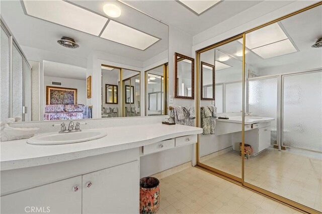 bathroom featuring a shower with door and vanity