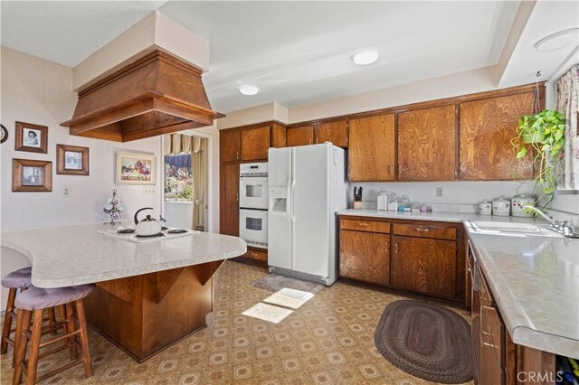 kitchen with a kitchen breakfast bar, sink, and white appliances