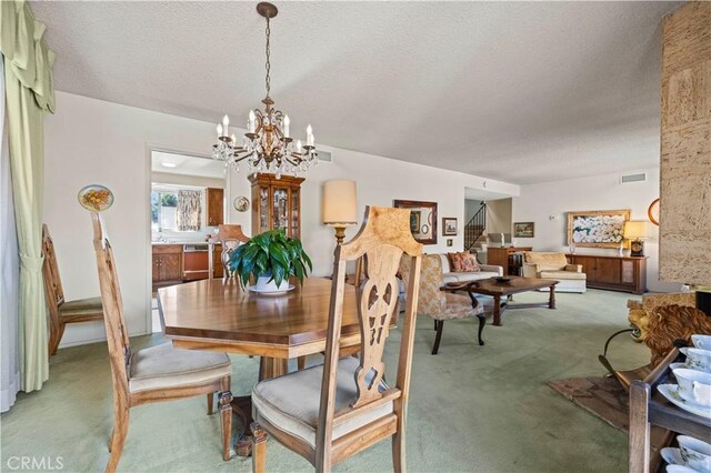 carpeted dining room featuring a chandelier and a textured ceiling